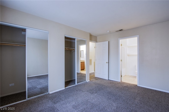 unfurnished bedroom featuring two closets, baseboards, visible vents, and carpet flooring