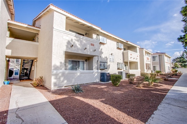 view of building exterior with a residential view, central AC, and stairway