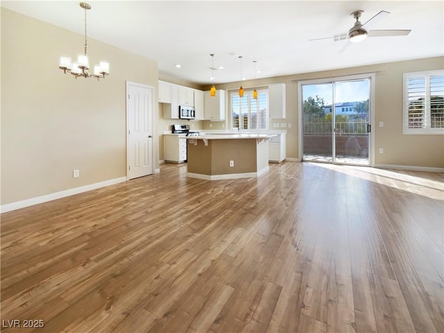 kitchen with open floor plan, white cabinetry, appliances with stainless steel finishes, light wood finished floors, and light countertops