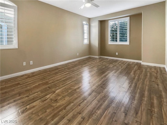 spare room with ceiling fan, baseboards, and dark wood-style flooring