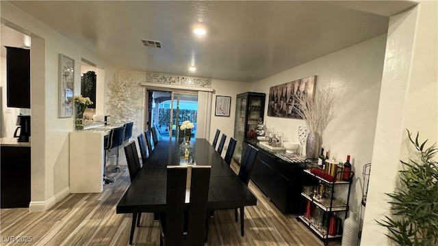 dining space featuring wood finished floors, visible vents, and baseboards