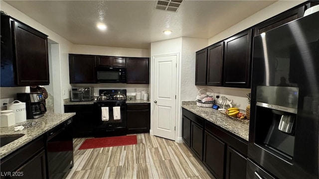 kitchen with visible vents, black appliances, light stone countertops, and light wood-style floors