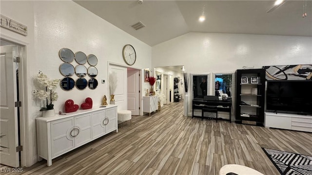 interior space featuring high vaulted ceiling, visible vents, and wood finished floors