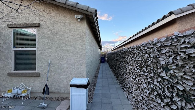 view of side of home with a patio, fence, and stucco siding