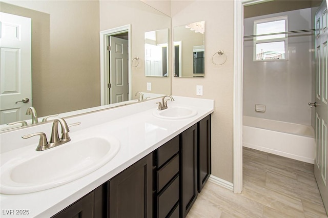 full bathroom with double vanity, shower / bath combination, baseboards, and a sink