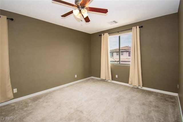 empty room featuring light carpet, ceiling fan, visible vents, and baseboards