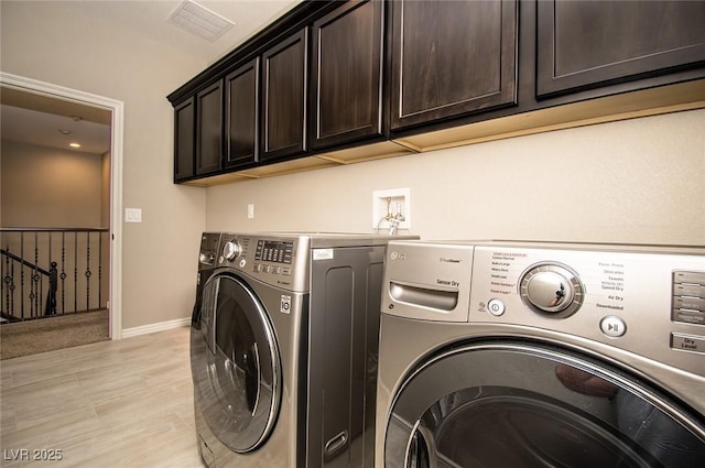 washroom featuring washer and dryer, cabinet space, visible vents, and baseboards