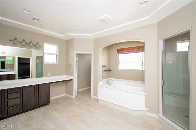 full bath with a bath, vanity, visible vents, and baseboards