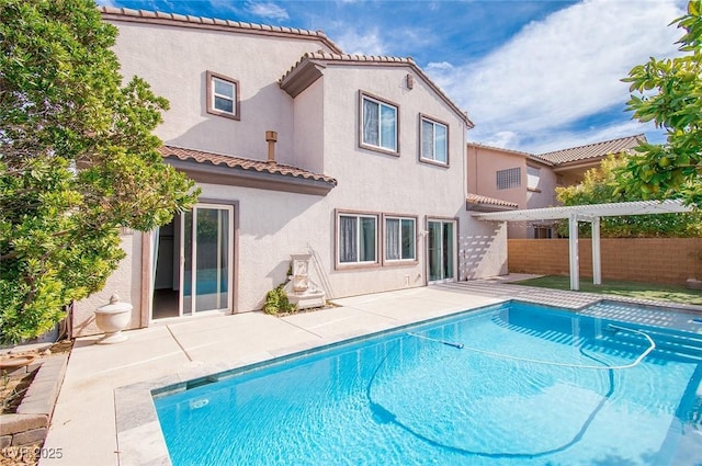 rear view of house with a tile roof, fence, a fenced in pool, a pergola, and stucco siding