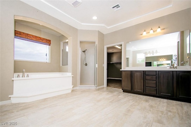 full bathroom featuring a garden tub, vanity, visible vents, baseboards, and a stall shower