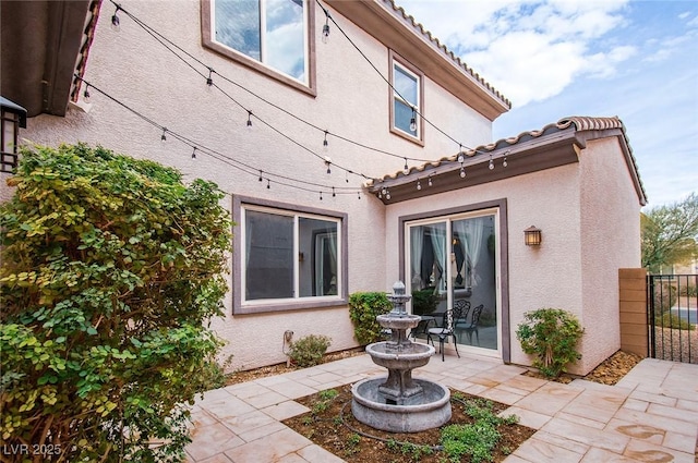 back of property featuring a tiled roof, a patio area, fence, and stucco siding