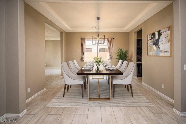 dining area featuring baseboards, a tray ceiling, and wood finish floors