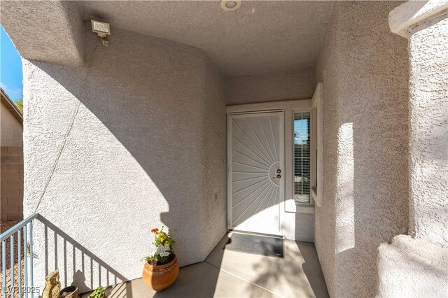 property entrance with a balcony and stucco siding