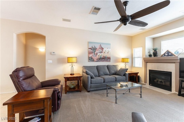 living room with visible vents, arched walkways, carpet flooring, a fireplace, and ceiling fan