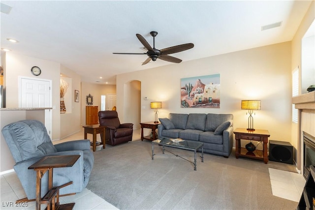 living room featuring arched walkways, visible vents, light colored carpet, and a tile fireplace