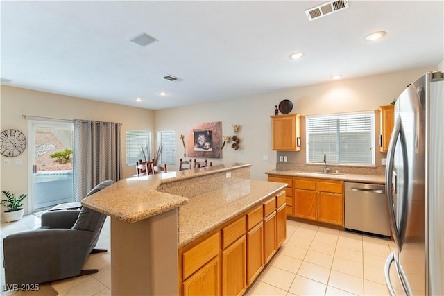 kitchen featuring visible vents, appliances with stainless steel finishes, a kitchen island, and a sink