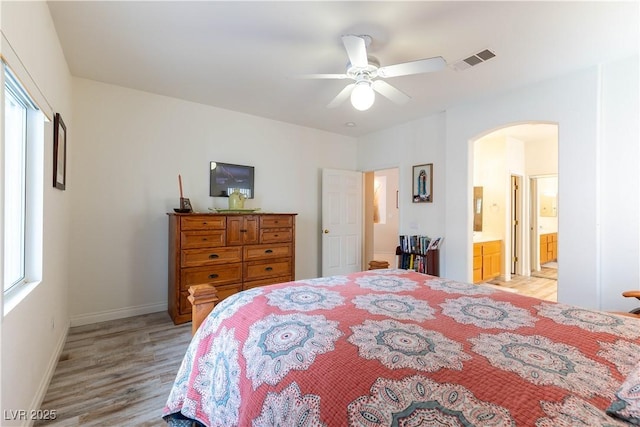 bedroom featuring multiple windows, arched walkways, visible vents, and light wood-type flooring