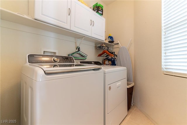 washroom featuring cabinet space, washing machine and dryer, and light tile patterned flooring