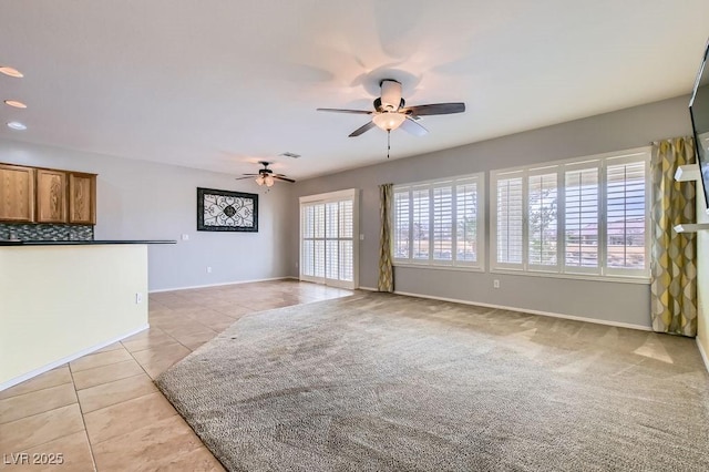 living room with a ceiling fan, visible vents, baseboards, light tile patterned flooring, and light carpet