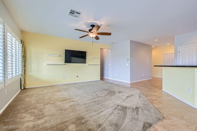 unfurnished living room featuring light carpet, visible vents, baseboards, and a ceiling fan