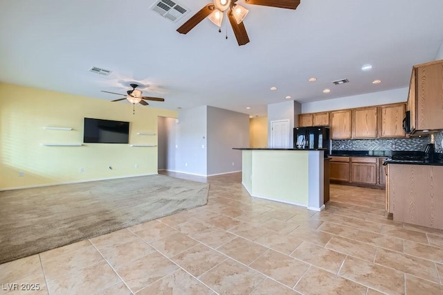 kitchen featuring dark countertops, tasteful backsplash, and visible vents