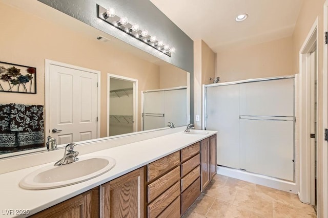 full bath with a shower stall, double vanity, and a sink