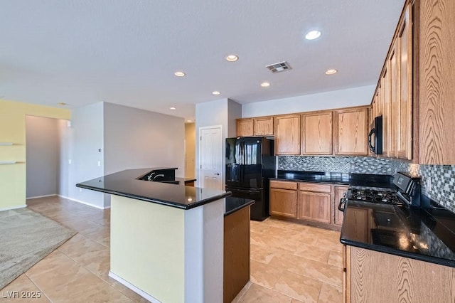 kitchen with visible vents, a kitchen island with sink, black appliances, dark countertops, and tasteful backsplash