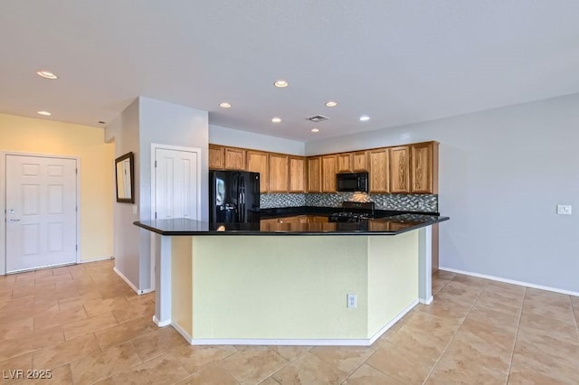 kitchen with dark countertops, visible vents, backsplash, brown cabinets, and black appliances