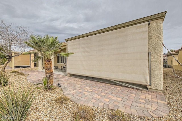 exterior space with stucco siding, cooling unit, and a patio area