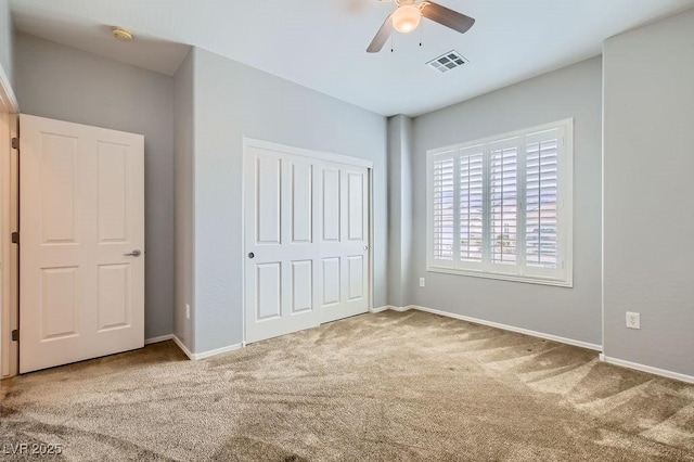 unfurnished bedroom featuring visible vents, baseboards, carpet flooring, a closet, and a ceiling fan