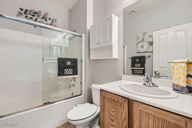 bathroom featuring visible vents, toilet, vanity, and bath / shower combo with glass door