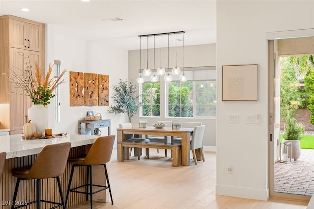 dining space featuring baseboards, light wood-style flooring, visible vents, and a wealth of natural light