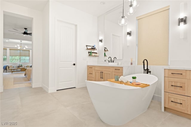 bathroom with ceiling fan with notable chandelier, a freestanding tub, vanity, and tile patterned floors