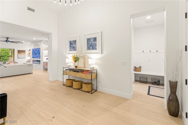 hallway featuring wood finished floors, visible vents, and baseboards