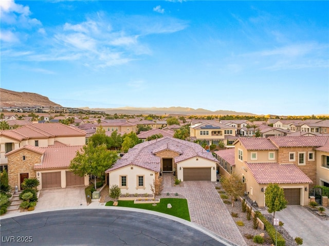 view of front of house featuring a residential view, a tiled roof, decorative driveway, a mountain view, and stucco siding