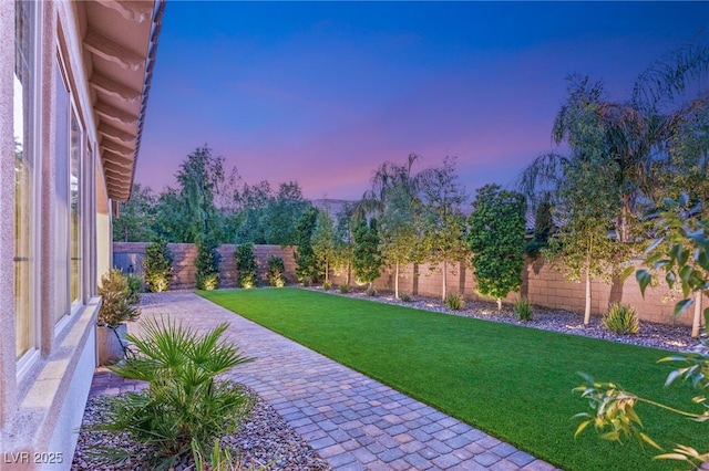 yard at dusk featuring a fenced backyard and a patio