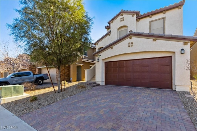 mediterranean / spanish home with decorative driveway, stucco siding, and a tiled roof