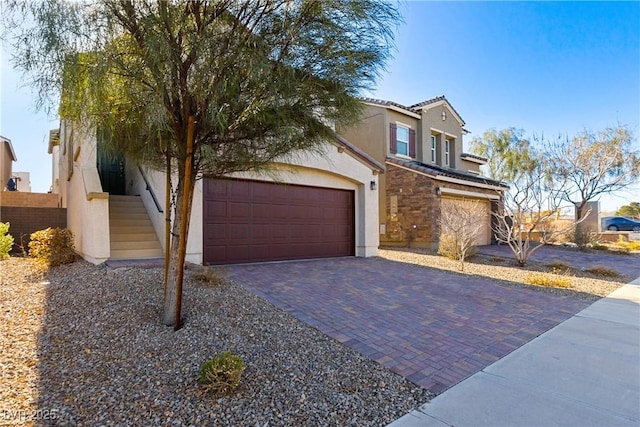 view of front of home with stucco siding, decorative driveway, stone siding, a garage, and a tiled roof