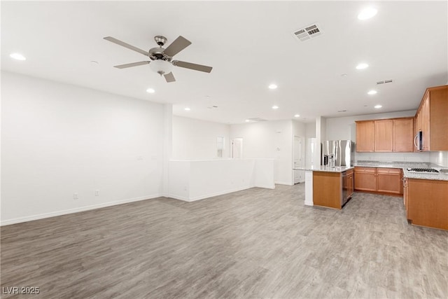 kitchen featuring visible vents, a kitchen island, open floor plan, stainless steel appliances, and light wood-style floors