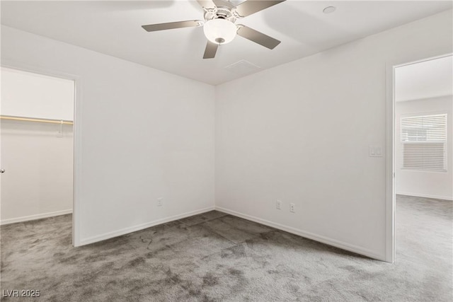 unfurnished bedroom with a walk in closet, a ceiling fan, and carpet floors