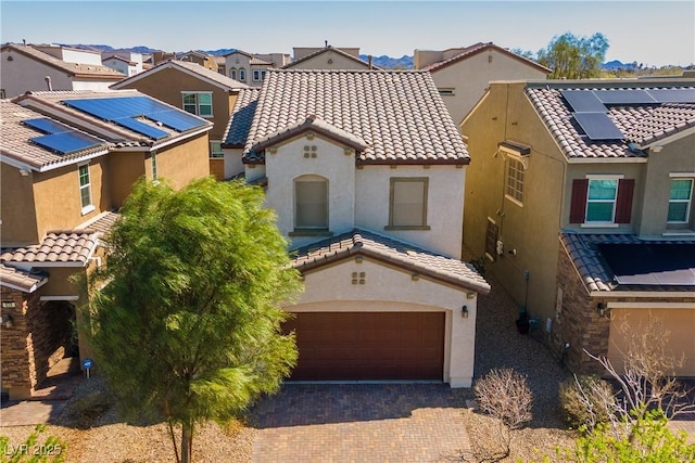 mediterranean / spanish-style house featuring a residential view, stucco siding, a tiled roof, and decorative driveway