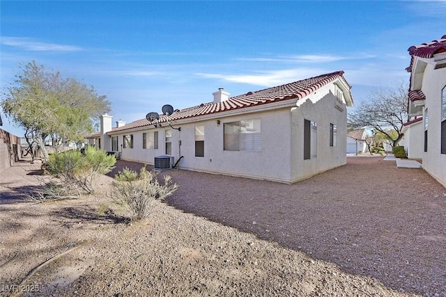 back of house featuring central air condition unit, a tiled roof, and stucco siding