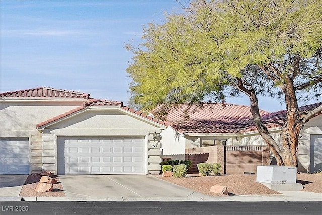 mediterranean / spanish house featuring a garage, concrete driveway, a tiled roof, and stucco siding