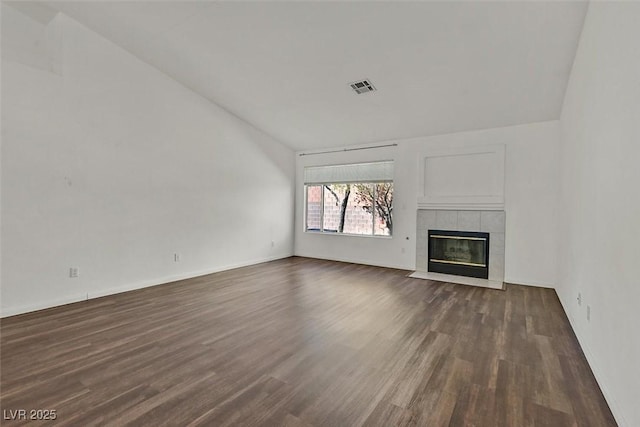 unfurnished living room featuring lofted ceiling, dark wood-type flooring, a fireplace, and visible vents