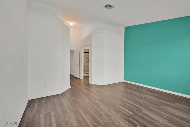 empty room with baseboards, visible vents, and wood finished floors