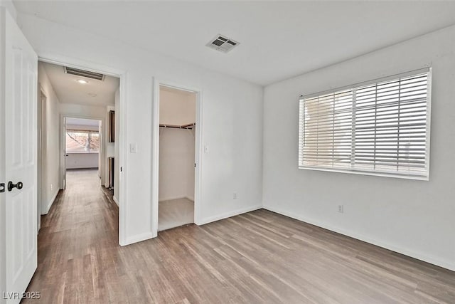 unfurnished bedroom featuring a closet, visible vents, baseboards, and wood finished floors