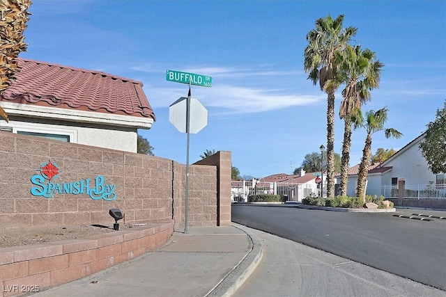 view of road with traffic signs, sidewalks, a gated entry, a residential view, and curbs