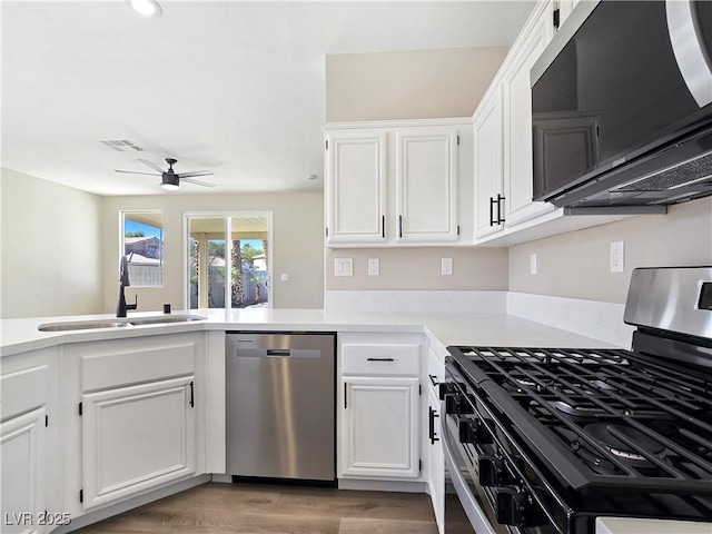 kitchen featuring visible vents, a sink, white cabinetry, stainless steel appliances, and light countertops