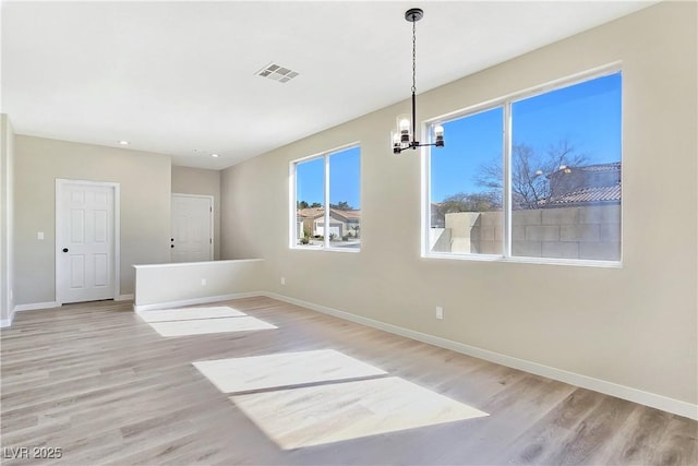 unfurnished dining area with a notable chandelier, visible vents, light wood-type flooring, and baseboards