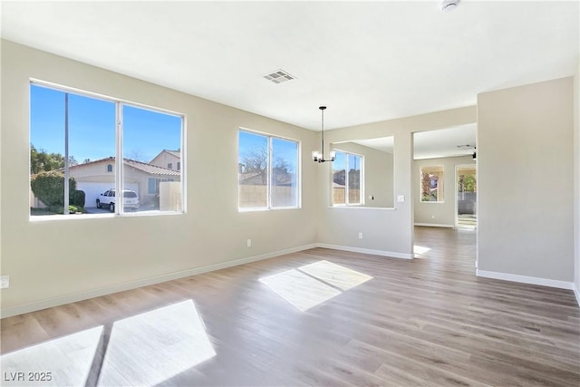 spare room with visible vents, baseboards, plenty of natural light, and wood finished floors